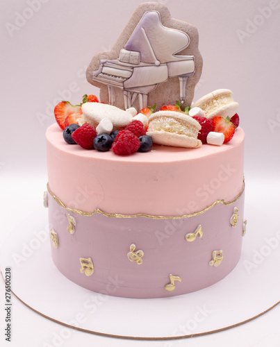 Cake decorated with gingerbread in the form of a piano, as well as berries and macaroons. On a white background. 