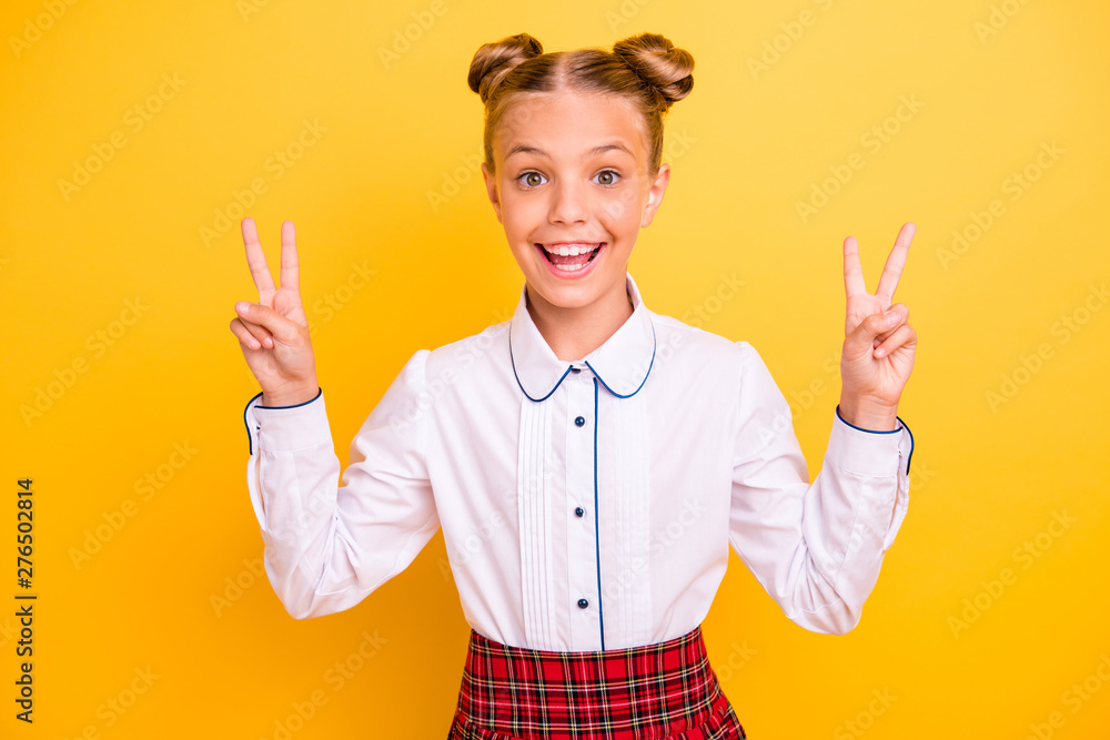 Close-up portrait of nice attractive cheerful cheery confident content optimistic pre-teen girl in white shirt showing double v-sign isolated on bright vivid shine yellow background Close-up portrait of nice attractive cheerful cheery confident content optimistic pre-teen girl in white shirt showing double v-sign isolated on bright vivid shine yellow background