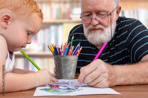 Obraz na plátně Teamwork between grandfather and grandson to color a drawing