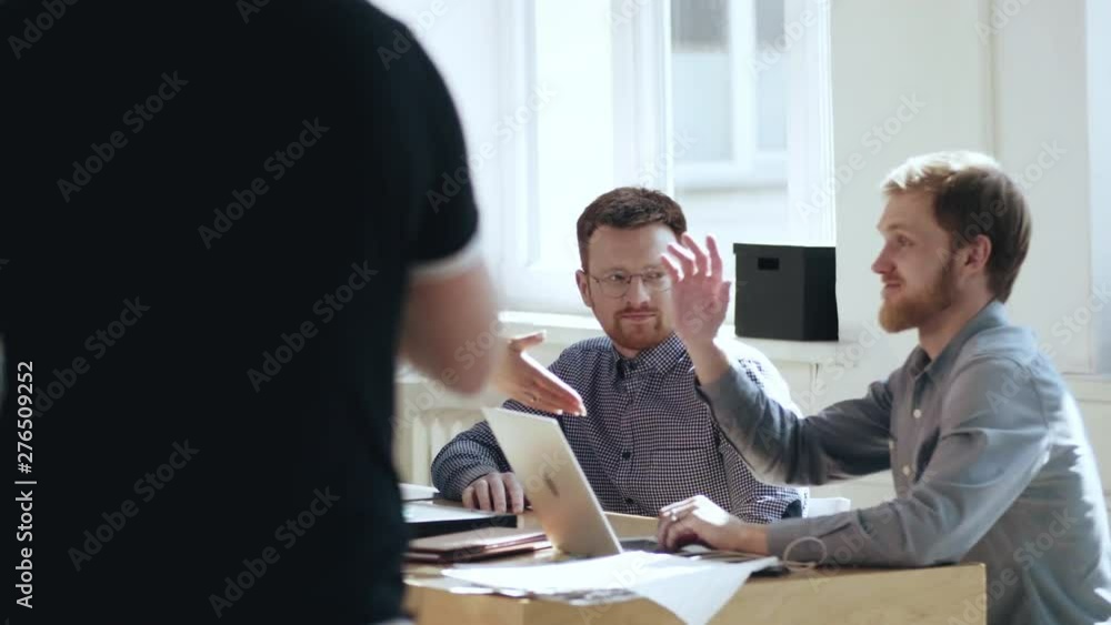 Happy relaxed young male boss businessman talking to smiling colleagues at modern loft office workplace table. Happy relaxed young male boss businessman talking to smiling colleagues at modern loft office workplace table.