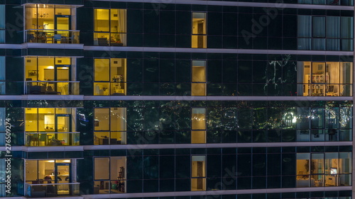 Glowing apartment windows at night in glass skyscraper timelapse