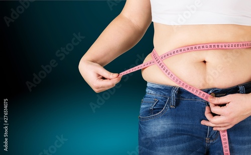 Close-up female figure with measuring tape on grey background