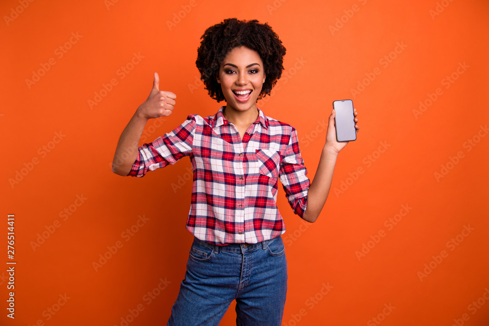 Photo of amazing wavy model lady hold hands telephone thumb up symbol approve cool quality wear casual checkered shirt isolated orange background Photo of amazing wavy model lady hold hands telephone thumb up symbol approve cool quality wear casual checkered shirt isolated orange background