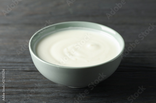 Bowl of sour cream yogurt on dark wooden background