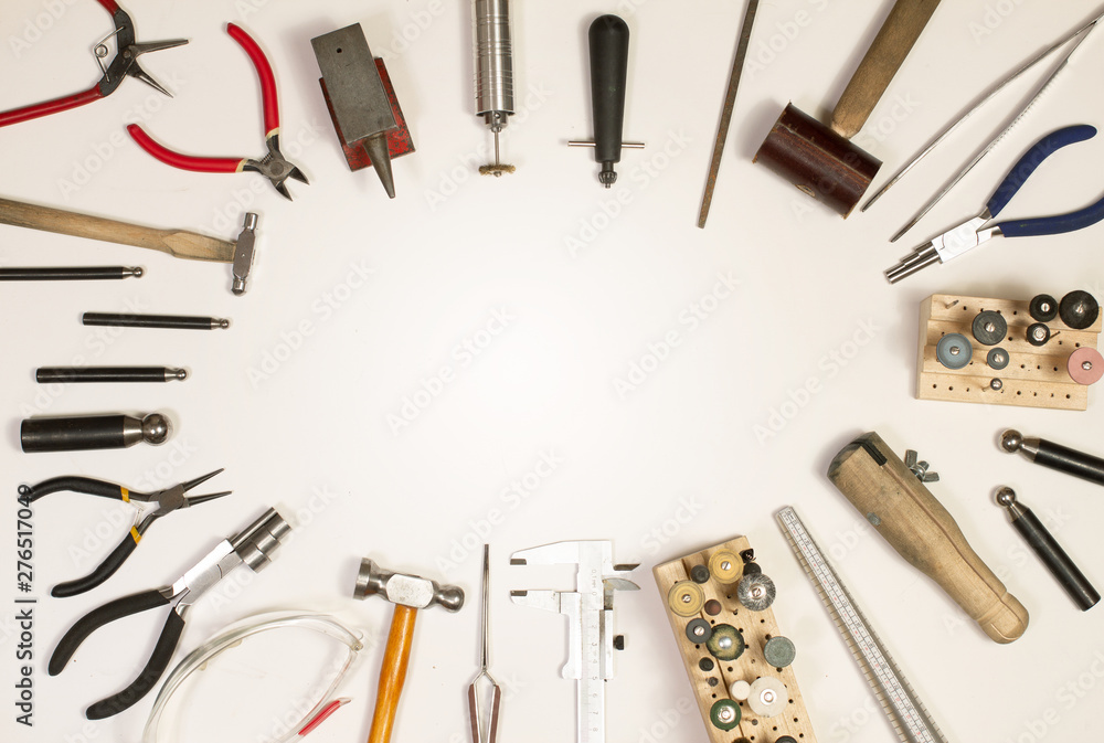 Top view of hands holding goldsmiths tools, jewelry objects. Tools over white background. Top view of hands holding goldsmiths tools, jewelry objects. Tools over white background.