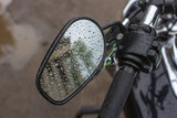 Reflection in the mirror. Raindrops on a motorcycle mirror. Traveling on two wheels. Motorcycle travel in any weather. Walk under the rain. Drops close up. The romance of biker life.