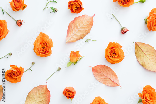 Creative floral arrangement. Fall red leaves and orange roses on white background. photo