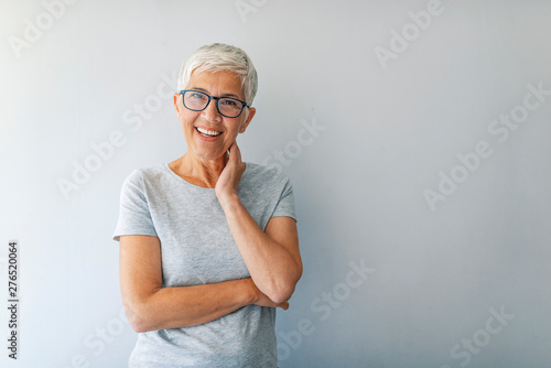 Close up portrait of a professional business woman smiling. Portrait of cheerful mature woman standing against grey wall. Close up portrait of beautiful older woman smiling and standing by wall photo
