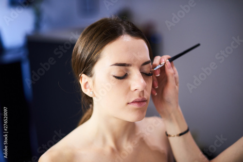 makeup artist doing perfect make up for the young model in photo studio