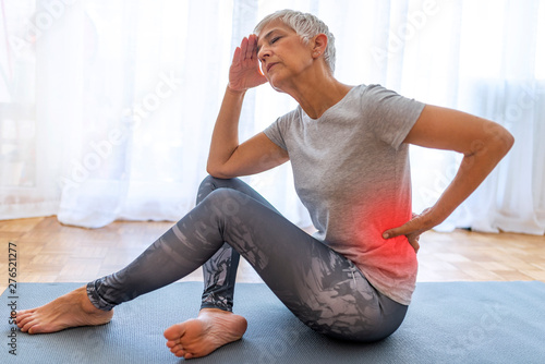 Matur Woman suffering from lower back pain. Mature woman resting with back pain. Female lower back pain. Senior woman injury suffering from backache cause of fitness. photo