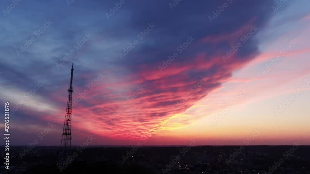 Dramatic colorful sunset over the beautiful evening cityscape from the viewpoint. Drone view of the television tower on the hill top above the modern city on island under amazing sky with clouds. Dramatic colorful sunset over the beautiful evening cityscape from the viewpoint. Drone view of the television tower on the hill top above the modern city on island under amazing sky with clouds.