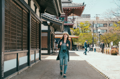 full length attractive korean backpacker relax sightseeing in shitennoji in osaka japan. beautiful lady traveler carrying camera and curious watching ancient architecture. local security man walking. © PR Image Factory