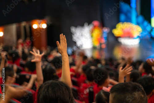 Children excitingly raise hands watching the performance in the theater photo