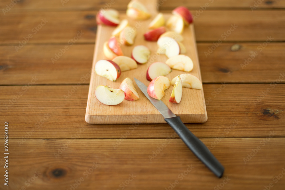 fruits, food cooking and eating concept - sliced apples and kitchen knife on wooden cutting board