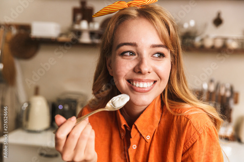 Cuadro en lienzo Happy cheerful young blonde girl chef at the kitchen holding tablespoon