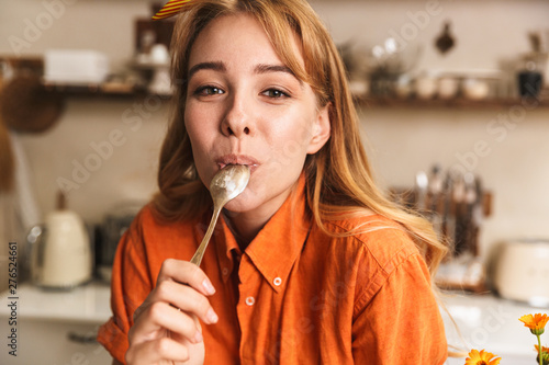Картината върху платно Happy cheerful young blonde girl chef at the kitchen holding tablespoon