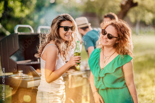 Close up portrait of girls drinking and laughing at backyard barbecue party