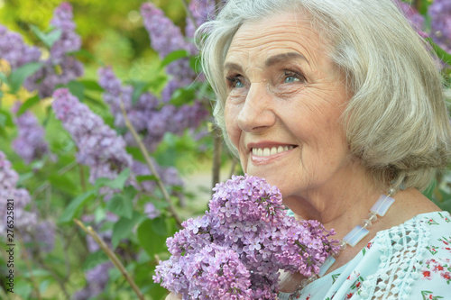Fototapeta Portrait of happy senior beautiful woman with lilacs