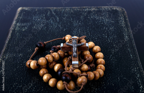 Rosary beads and prayer book on dark background. photo