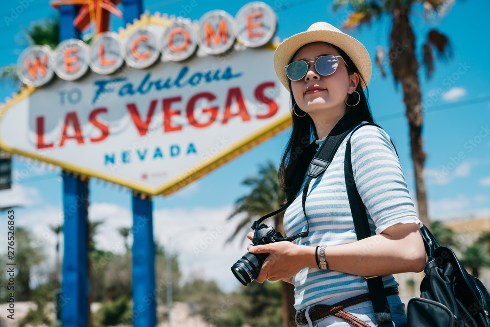 Young pretty hipster cheerful girl traveler walking on street at sunny day.  female photographer holding vintage camera having fun alone on summer  outdoor. tourist visit famous sign fabulous las vegas Stock-Foto