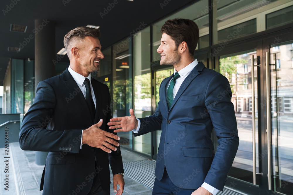 Portrait closeup of two joyful businessmen partners shaking hands outside job center during working meeting