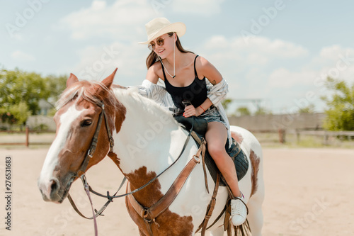 woman in cowboy hat riding horse on a ranch © Anastasia