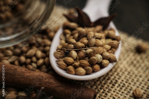 Coriander seeds on a ceramic spoon with cinnamon and star anise. Close-up, selective focus and shallow DOF