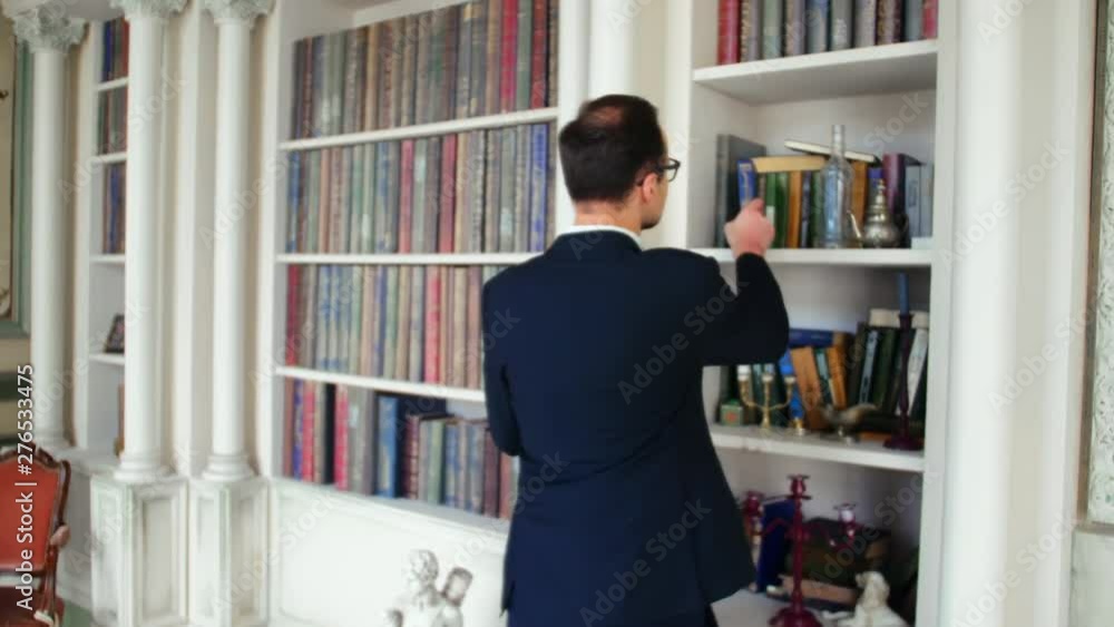 Man takes a book from a shelf in a public library Man takes a book from a shelf in a public library