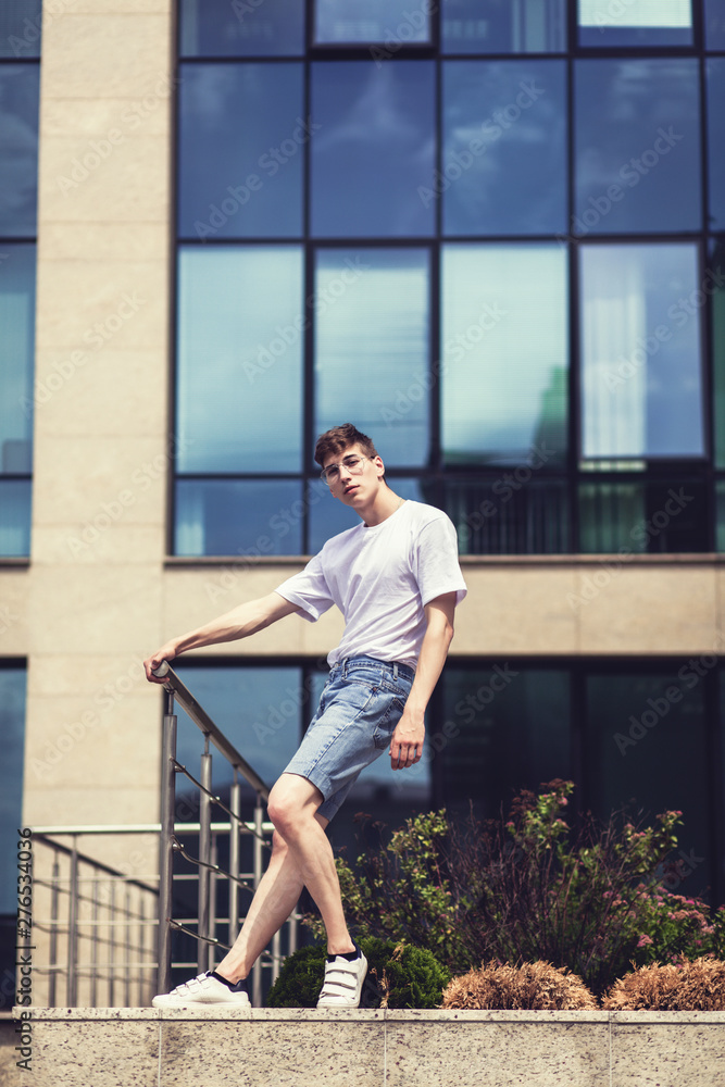 Happy young man posing outdoor in denim shorts