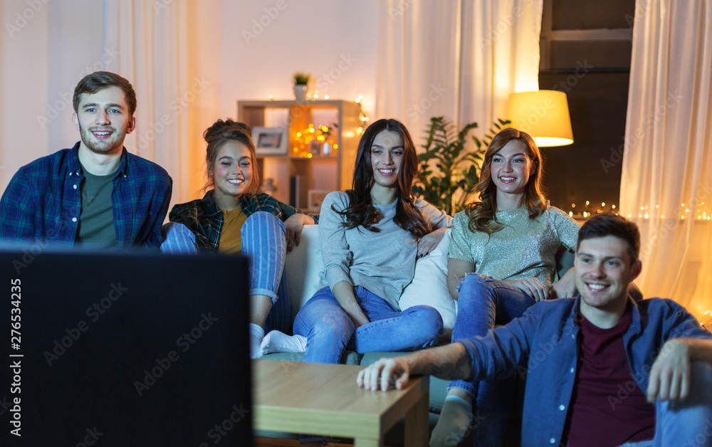 friendship, leisure, people and entertainment concept - happy friends watching tv at home in evening - obrazy, fototapety, plakaty 