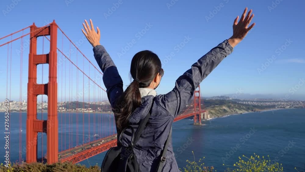 Woman enjoying beautiful landscape view on famous iron bridge standing back on top of mountain by ocean sea in Lisbon Portugal. carefree girl love freedom raising arms sightseeing golden gate bridge. Woman enjoying beautiful landscape view on famous iron bridge standing back on top of mountain by ocean sea in Lisbon Portugal. carefree girl love freedom raising arms sightseeing golden gate bridge.