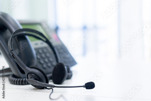 close up soft focus on headset with telephone devices at office desk for customer service support concept	 photo