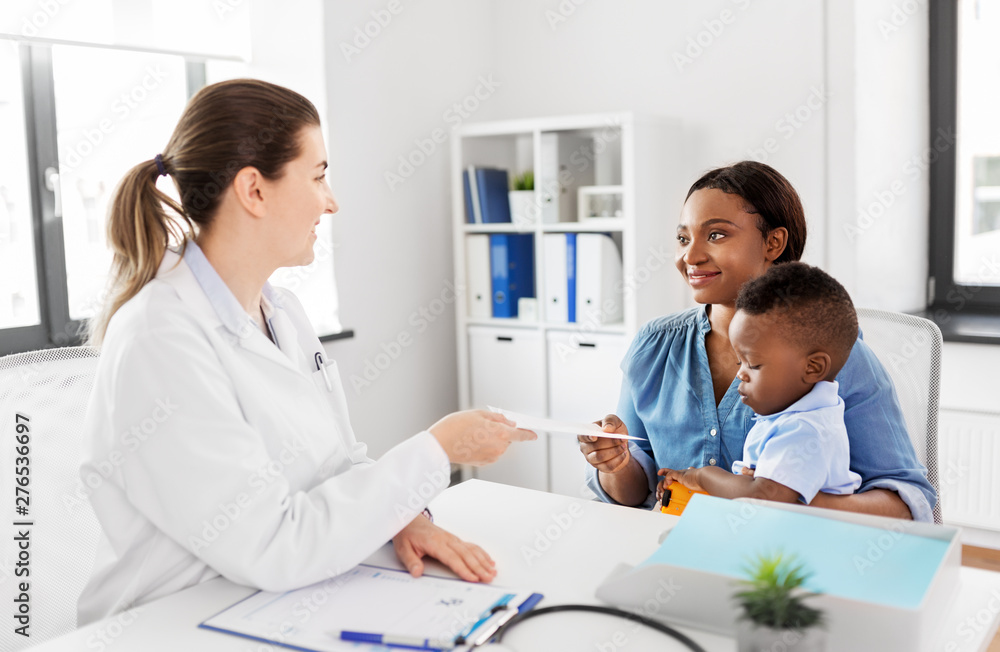 medicine, healthcare and pediatry concept - caucasian doctor giving prescription to african american mother with baby son at clinic medicine, healthcare and pediatry concept - caucasian doctor giving prescription to african american mother with baby son at clinic