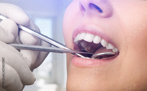 Woman teeth and a dentist mouth mirror on background