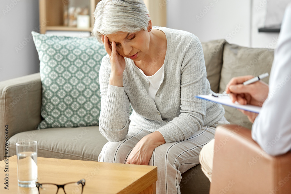 geriatric psychology, mental therapy and old age concept - sad unhappy senior woman patient and psychologist with clipboard taking notes at psychotherapy session geriatric psychology, mental therapy and old age concept - sad unhappy senior woman patient and psychologist with clipboard taking notes at psychotherapy session