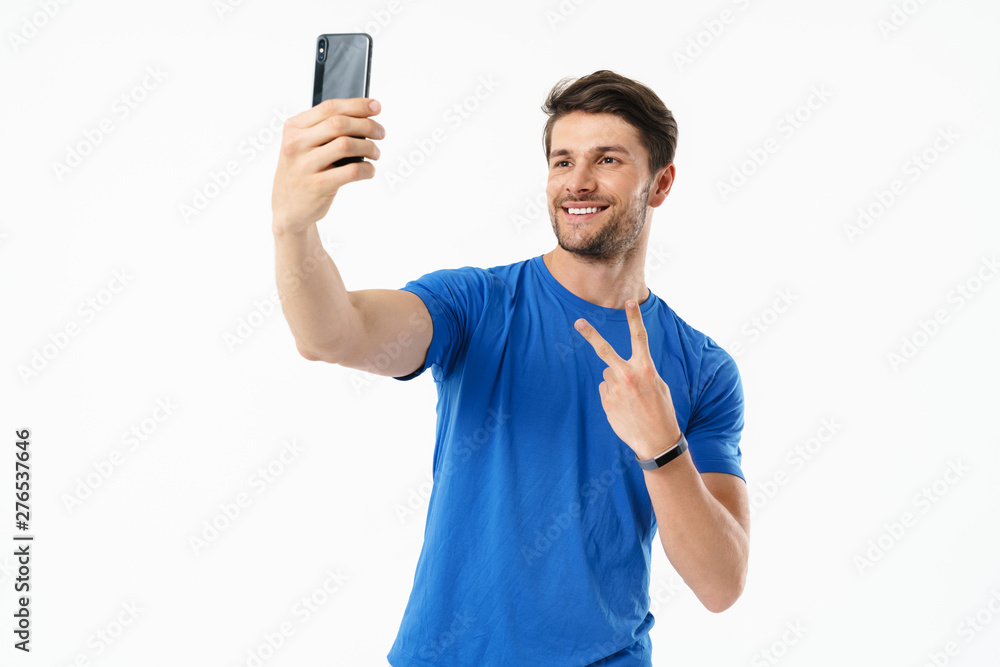 Photo of caucasian man in casual t-shirt showing peace sign and taking selfie on cellphone Photo of caucasian man in casual t-shirt showing peace sign and taking selfie on cellphone