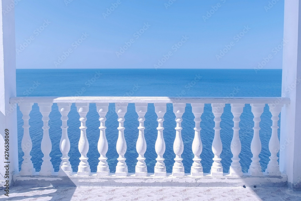 Classic white terrace with decorative fence and sea view om waterfront at sunny day.