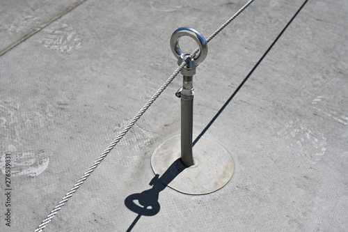 Photos A belaying eye with a steel rope on the roof in the afternoon glow of the sun