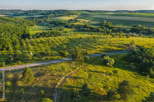 Fototapeta Naklejka Na Ścianę i Meble -  Aerial drone flight over hilly landscape. Ravine between hills with trees and bushes. Sloping hills covered with trees and green grass from bird sight.