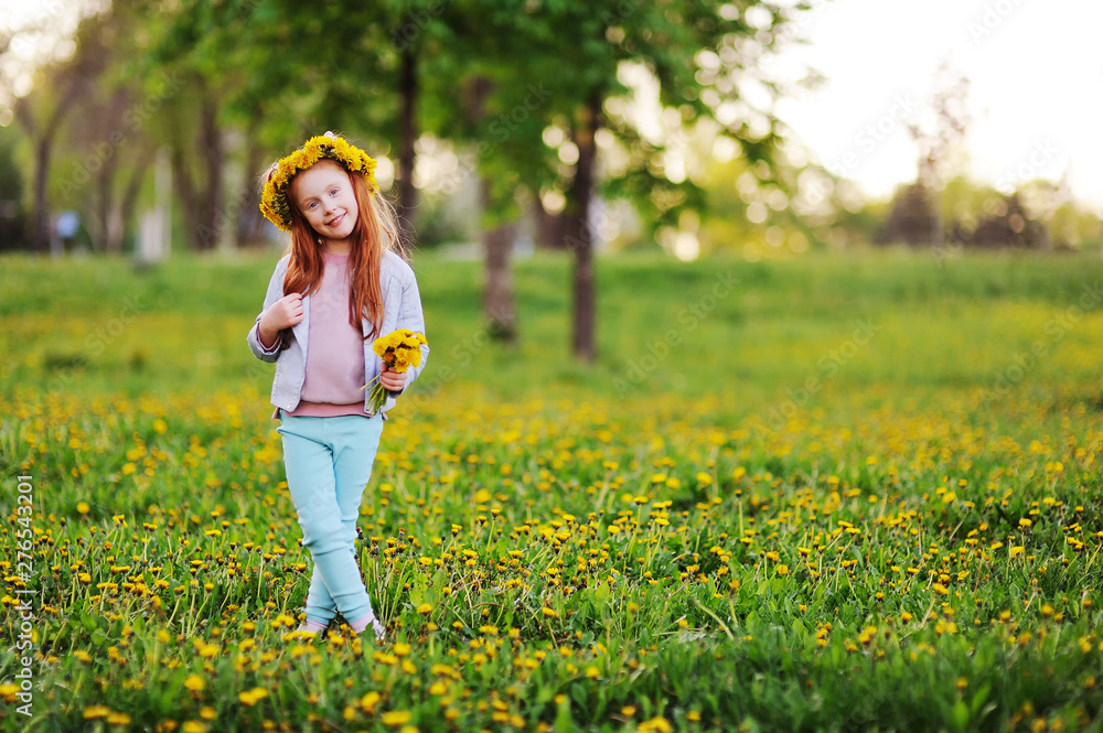a little girl with red hair smiles against a field of dandelions and green grass. Summer, childhood, holidays. space for text, copy space a little girl with red hair smiles against a field of dandelions and green grass. Summer, childhood, holidays. space for text, copy space