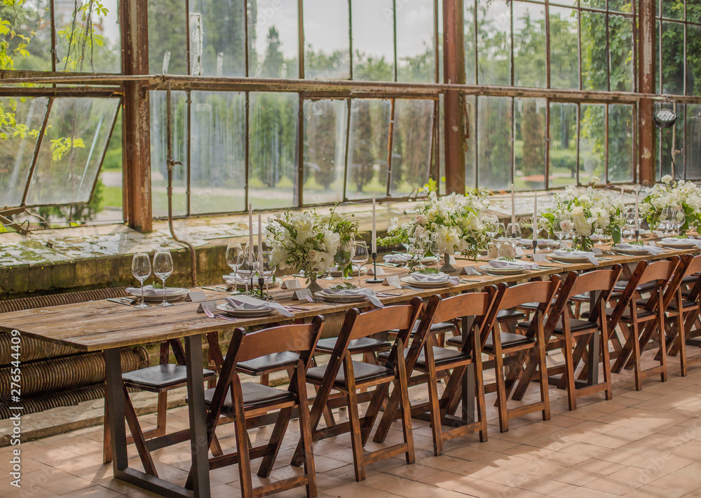 Banquet table set and decorated with flower arrangements and candle holders with candles