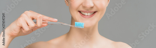 panoramic shot of happy naked woman holding toothbrush near teeth isolated on grey