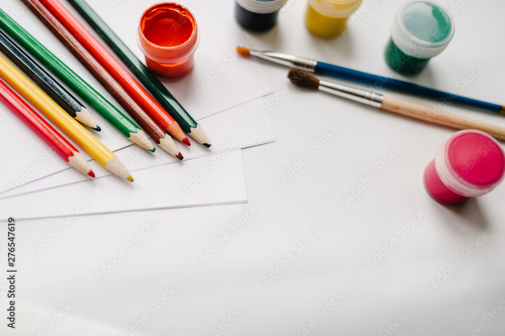 The workspace of artist for drawing. Place for text, design.Colored pencils, watercolor, paints, brush, sketchbook, white paper isolated on background table. Top view of art supplies. Product mockup. The workspace of artist for drawing. Place for text, design.Colored pencils, watercolor, paints, brush, sketchbook, white paper isolated on background table. Top view of art supplies. Product mockup.