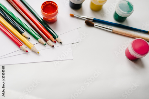 The workspace of artist for drawing. Place for text, design.Colored pencils, watercolor, paints, brush, sketchbook, white paper isolated on background table. Top view of art supplies. Product mockup.