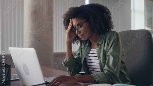 Stressful young businesswoman at desk using laptop