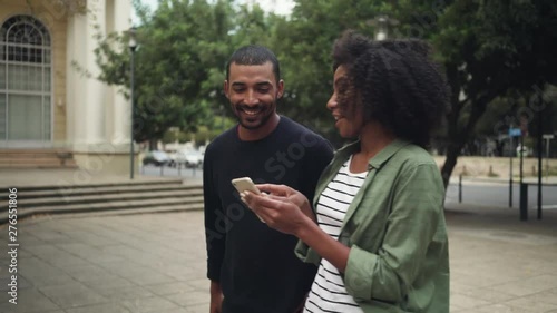 Boyfriend looking at girlfriend's mobile phone while walking on street