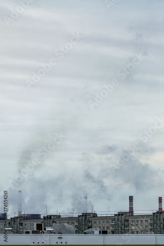 vertical banner of industrial chimneys on a cloudy sky background with heavy smoke causing air pollution as environmental problem