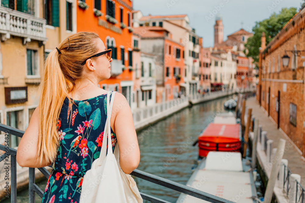 Young woman standing on the bridge in Venice, Italy enjoying the view