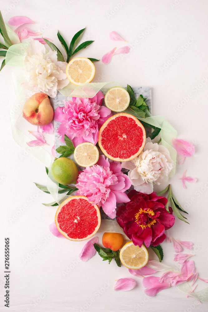 Plakat Still life with fresh assorted exotic fruits and peony flowers on white background. Festive flower and fruit composition. Wedding decor