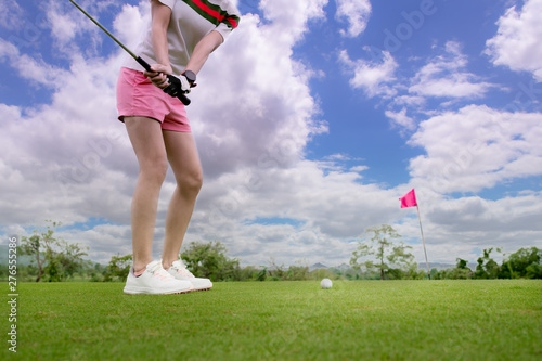 woman golf player in action of being chip golf ball from rough of fairway to the destination green at day light sky. photo